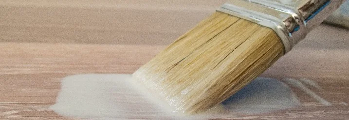 Pinsel trägt Lack auf Holz auf